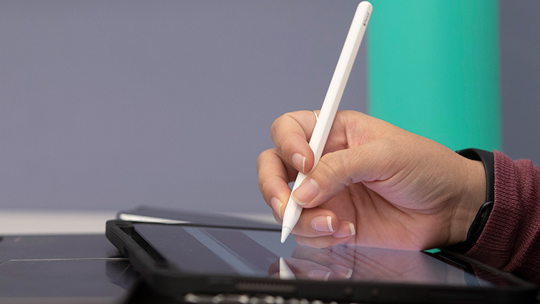 Close-up of student using an iPad pen and iPad.